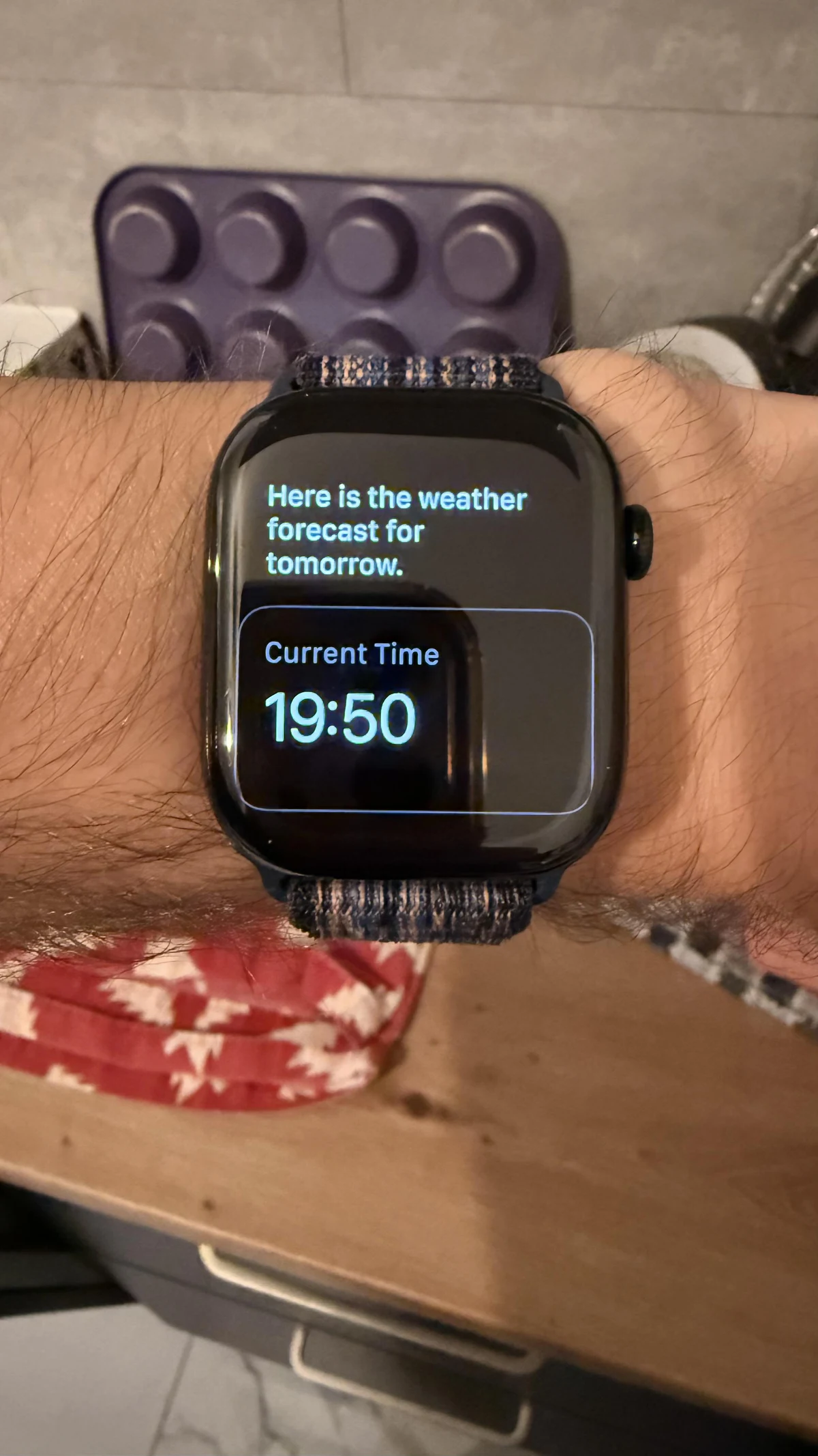 An Apple Watch says it is showing tomorrow’s weather forecast but displays a Current Time card reading 19:50.